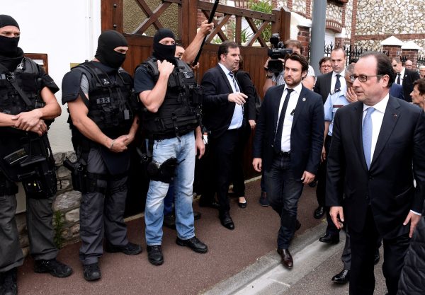 French President Francois Hollande (R) stands by members of the RAID, the French national police intervention group, as he arrives after a hostage-taking at a church in Saint-Etienne-du-Rouvray, France, July 26, 2016. A priest was killed with a knife and another hostage seriously wounded in an attack on a church that was carried out by assailants linked to Islamic State.    REUTERS/Boris Maslard/Pool