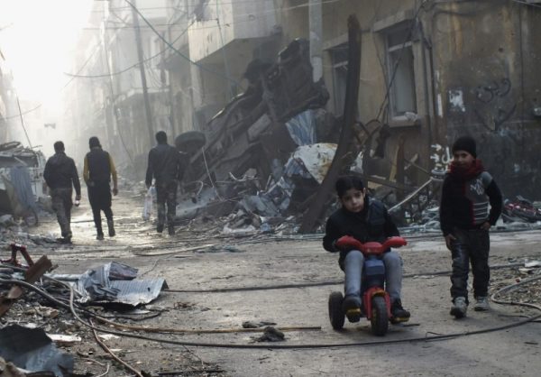 A boy rides on a tricycle along a damaged street in the besieged area of Homs, Syria. REUTERS/Yazan Homsy