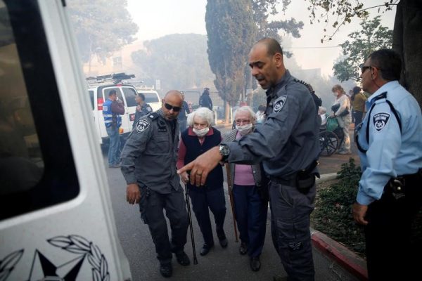 Israeli policemen assist elderly people as they are evacuated during a wildfire in the northern city of Haifa, Israel November 24, 2016. REUTERS/Baz Ratner